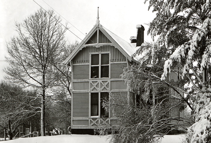 Two story cabin in snow with trees surrounding