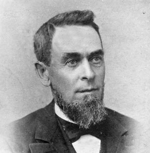 Black and white image of bearded white man wearing suit