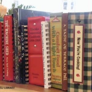 Color photo of a row of cookbooks sitting on a shelf